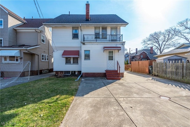 rear view of property with entry steps, a lawn, a chimney, and fence