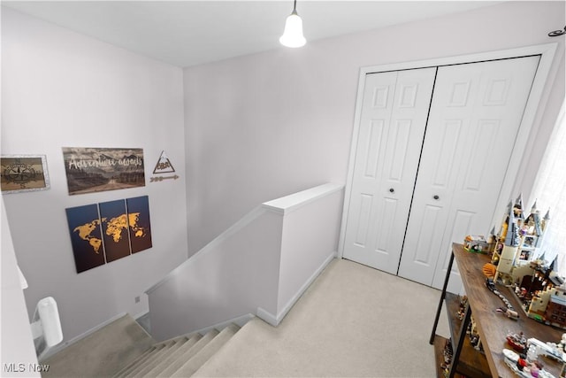 corridor with an upstairs landing and light colored carpet