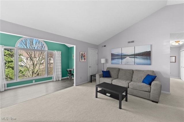 carpeted living area with baseboards and high vaulted ceiling