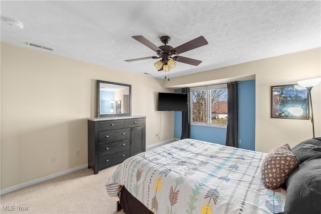 bedroom featuring a ceiling fan, baseboards, visible vents, a textured ceiling, and light carpet