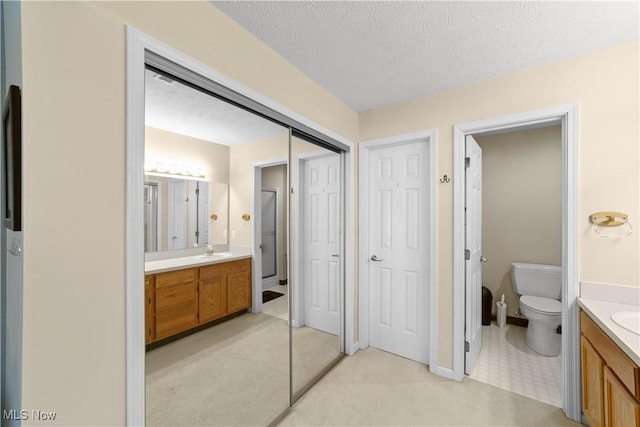 full bathroom with toilet, vanity, and a textured ceiling