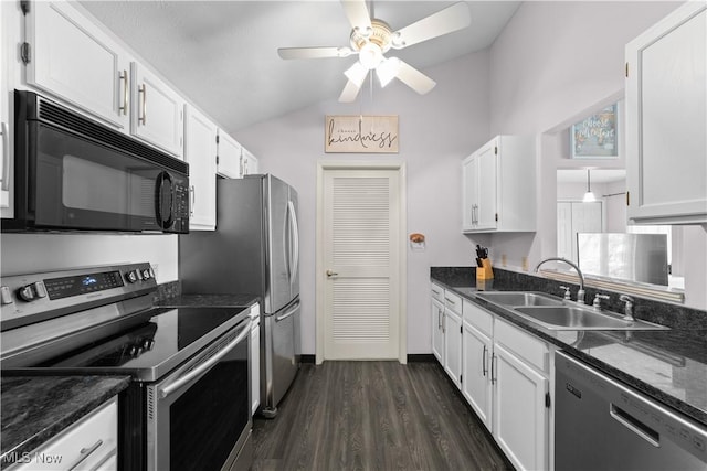 kitchen with dark wood finished floors, vaulted ceiling, stainless steel appliances, white cabinetry, and a sink