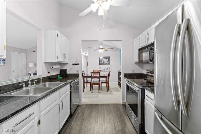 kitchen with white cabinets, appliances with stainless steel finishes, lofted ceiling, and a sink