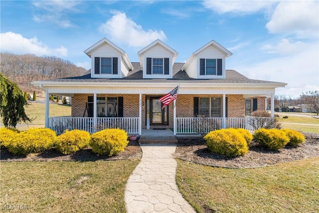 view of front of house featuring brick siding, covered porch, and a front lawn