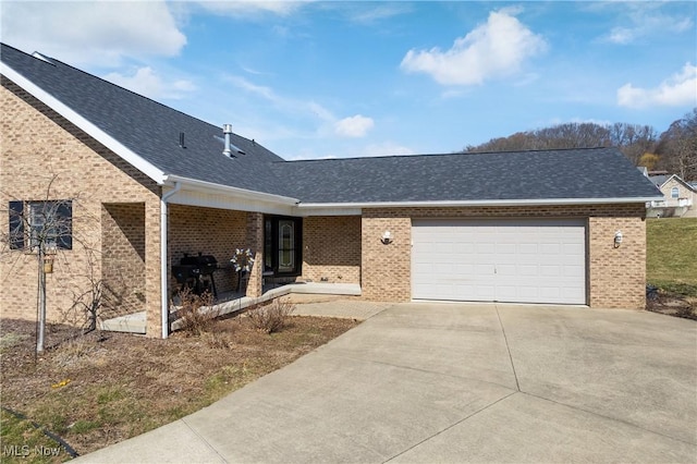 single story home with a garage, brick siding, concrete driveway, and a shingled roof