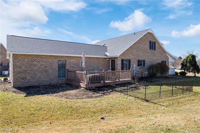 back of house with a deck, fence, a yard, roof with shingles, and brick siding