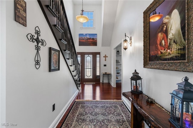 entryway with stairway, baseboards, a high ceiling, and wood finished floors