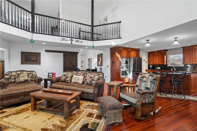 living room with a barn door, recessed lighting, and wood finished floors