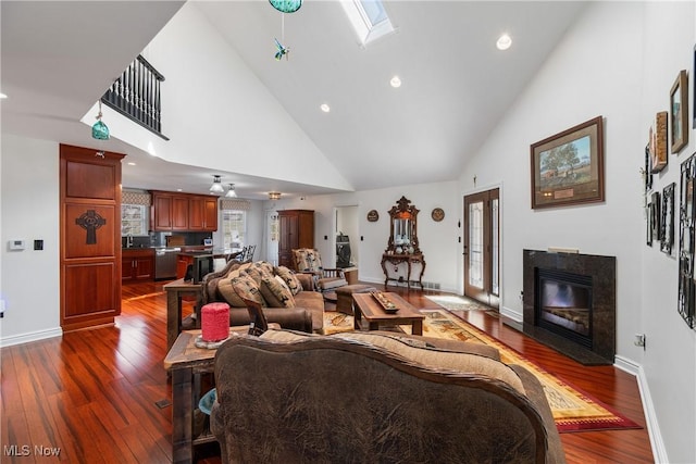 living room with dark wood-style floors, a fireplace, a skylight, and baseboards