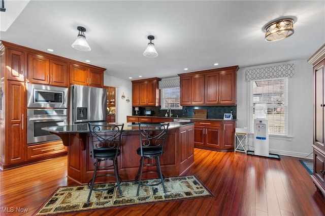 kitchen with backsplash, a center island, a kitchen bar, dark wood-style floors, and stainless steel appliances