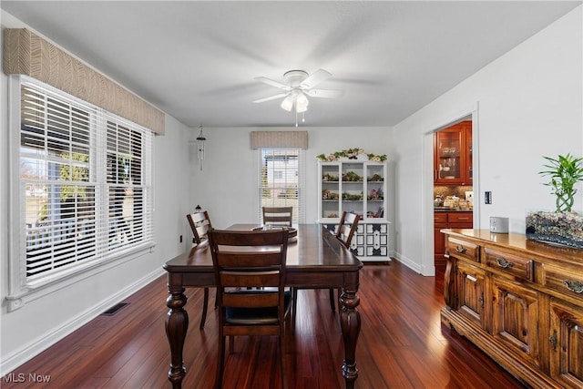 dining space featuring visible vents, ceiling fan, baseboards, and dark wood-style flooring