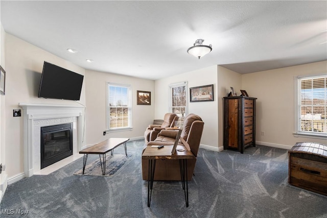 carpeted living room featuring a glass covered fireplace and baseboards