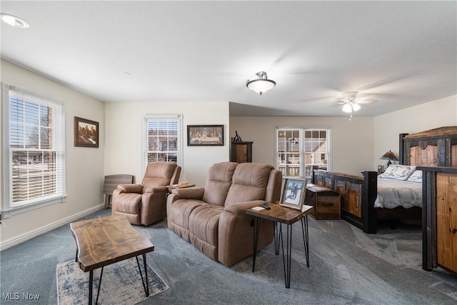 living room featuring baseboards, a ceiling fan, and carpet