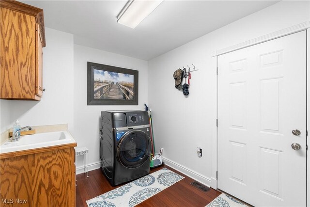 laundry area featuring washer / clothes dryer, dark wood-type flooring, a sink, baseboards, and cabinet space