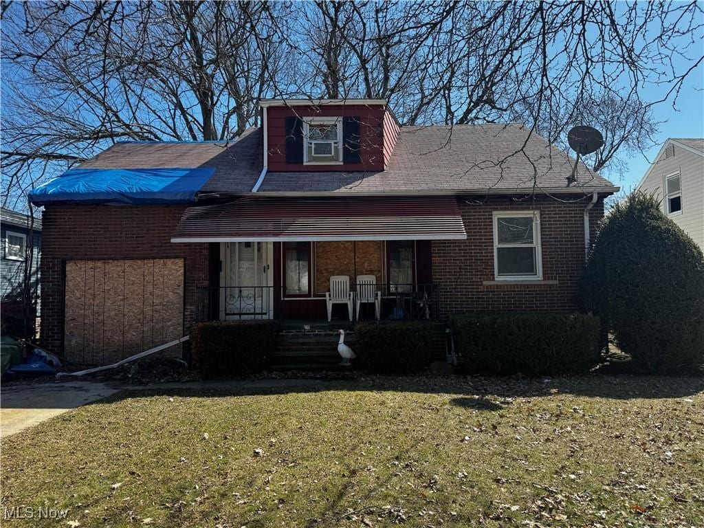 bungalow featuring a front lawn, brick siding, and covered porch