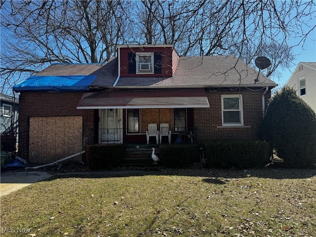 bungalow featuring a front lawn, brick siding, and covered porch