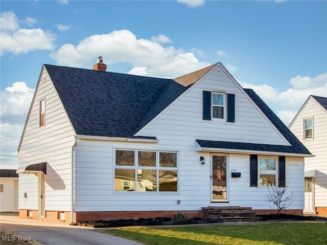 view of front of house featuring a chimney, roof with shingles, and a front yard