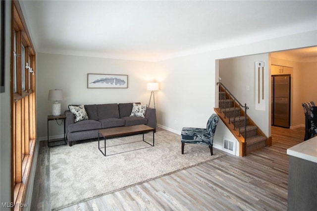 living area with stairway, baseboards, visible vents, and wood finished floors