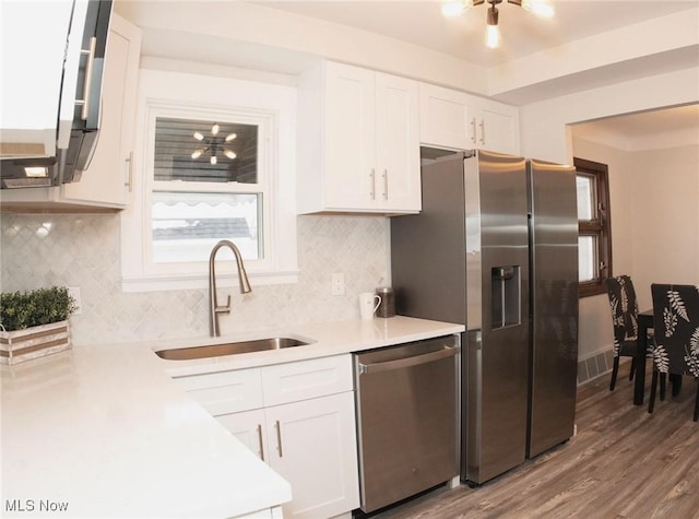 kitchen featuring a sink, wood finished floors, white cabinetry, appliances with stainless steel finishes, and light countertops