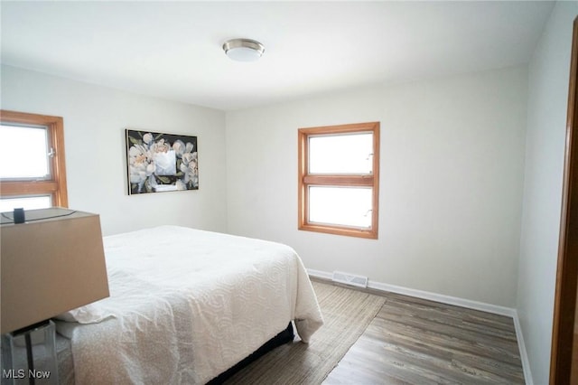 bedroom with visible vents, baseboards, and wood finished floors