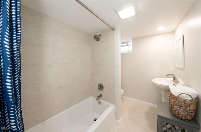 full bathroom with toilet, shower / bath combo with shower curtain, baseboards, and a sink