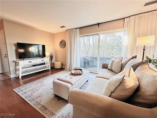 living area with visible vents, a textured ceiling, baseboards, and wood finished floors