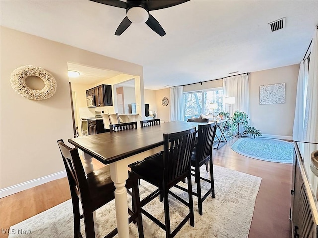 dining area with visible vents, baseboards, ceiling fan, and light wood finished floors