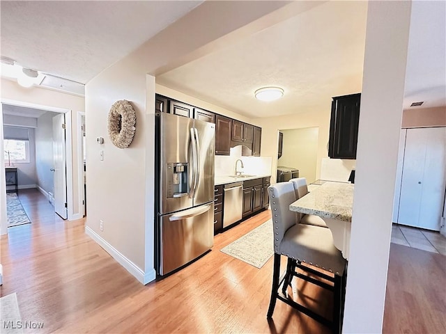 kitchen featuring visible vents, baseboards, light wood-type flooring, appliances with stainless steel finishes, and a sink