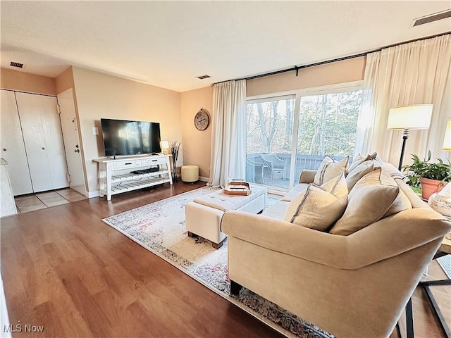 living room with visible vents, baseboards, and wood finished floors