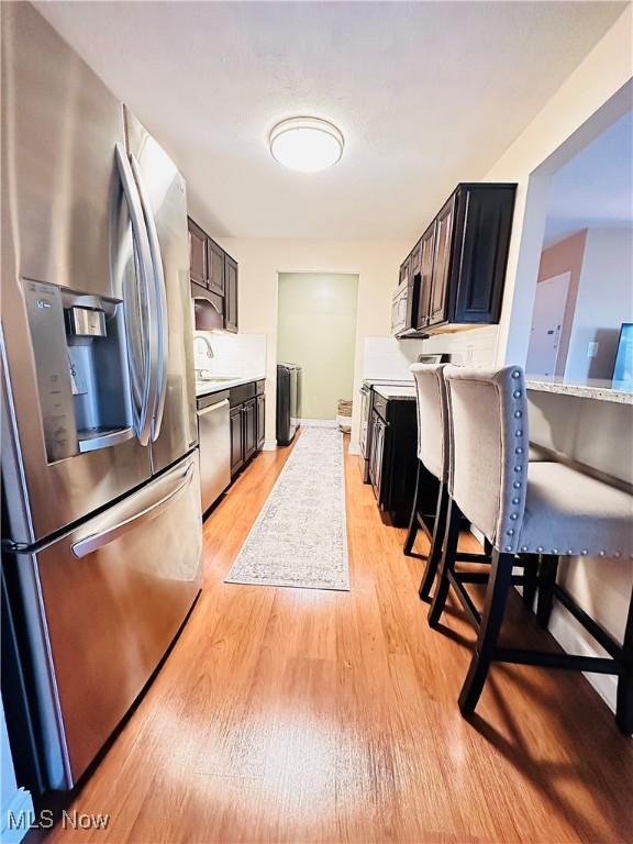 kitchen with a sink, light countertops, light wood finished floors, and stainless steel appliances