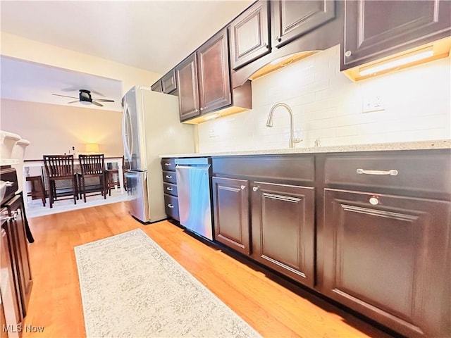 kitchen with light wood-style flooring, a sink, ceiling fan, appliances with stainless steel finishes, and tasteful backsplash