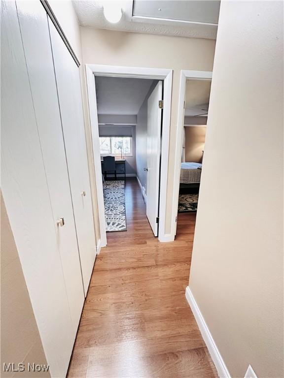 corridor with baseboards and light wood finished floors