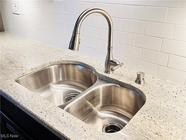 room details featuring tasteful backsplash, light stone counters, and a sink