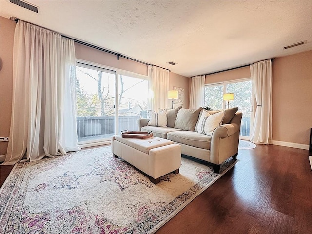 living area with wood finished floors, visible vents, and a textured ceiling