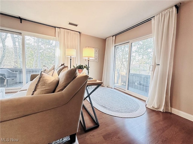 living area with wood finished floors, visible vents, and baseboards