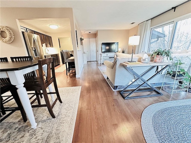 living area featuring light wood finished floors, visible vents, and baseboards