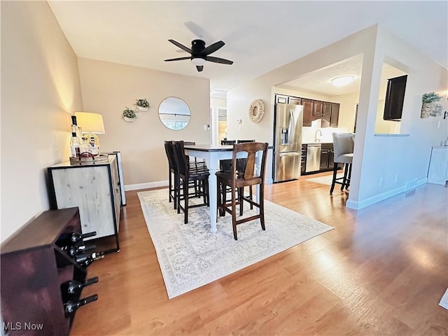 dining area featuring baseboards, light wood finished floors, and ceiling fan