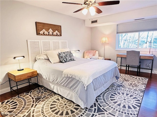 bedroom featuring visible vents, a ceiling fan, baseboards, and wood finished floors