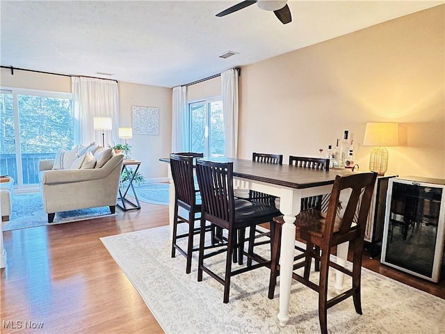 dining room with visible vents, beverage cooler, a ceiling fan, a textured ceiling, and wood finished floors