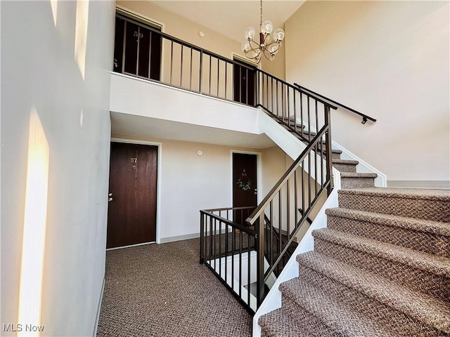 stairs with a high ceiling, a notable chandelier, carpet, and baseboards