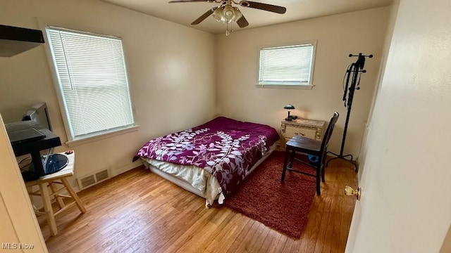 bedroom with visible vents, baseboards, wood finished floors, and a ceiling fan