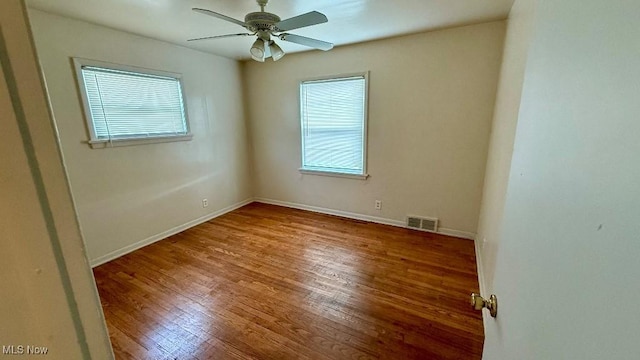 spare room featuring baseboards, wood finished floors, visible vents, and ceiling fan