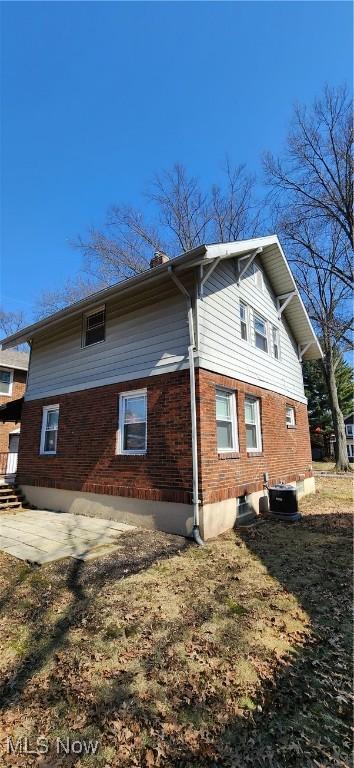 view of property exterior with brick siding, a patio area, and central AC unit