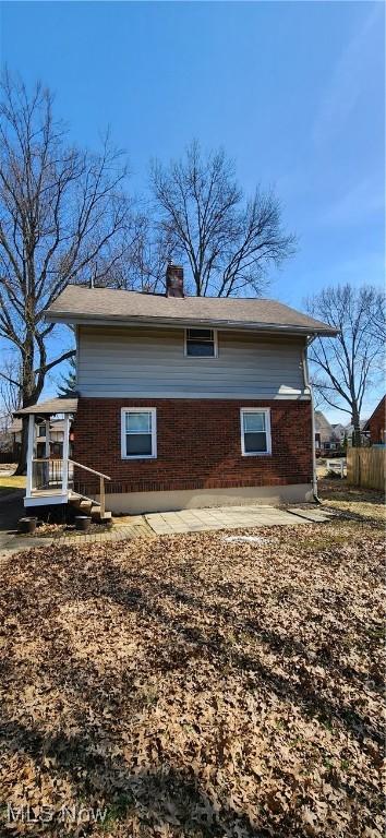 view of property exterior with brick siding and a chimney