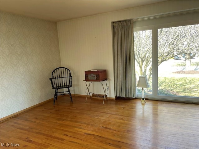 unfurnished room with baseboards, wood finished floors, and wallpapered walls