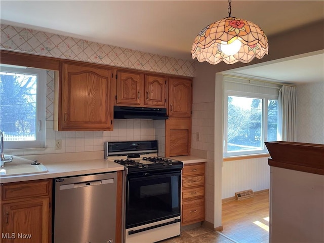 kitchen with gas stove, visible vents, wallpapered walls, under cabinet range hood, and dishwasher