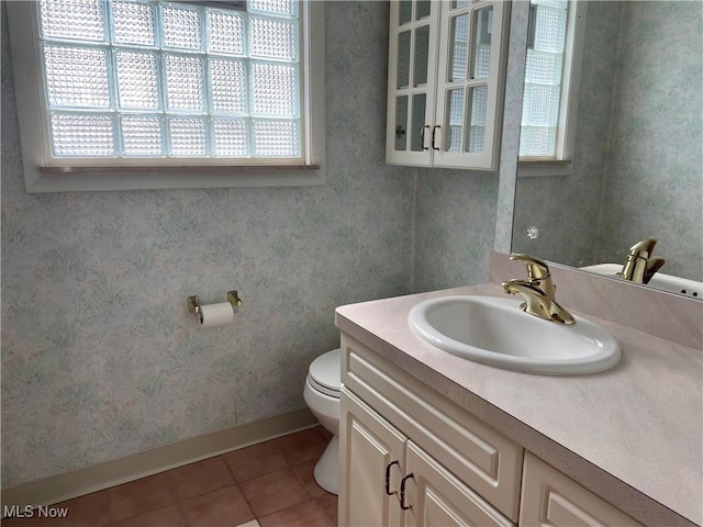 bathroom featuring vanity, baseboards, wallpapered walls, tile patterned floors, and toilet