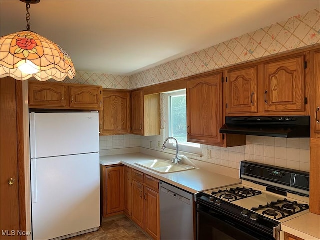 kitchen featuring wallpapered walls, range with gas stovetop, stainless steel dishwasher, and freestanding refrigerator