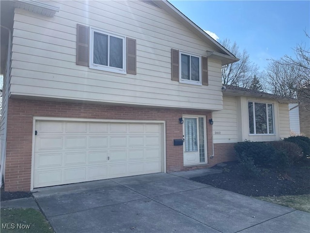 tri-level home featuring concrete driveway, brick siding, and a garage