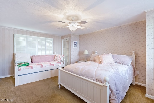 carpeted bedroom with baseboards, wallpapered walls, ceiling fan, ornamental molding, and a closet